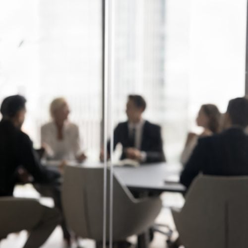 Group,Of,Businesspeople,Negotiating,Gathered,In,Modern,Conference,Room,,Blurred
