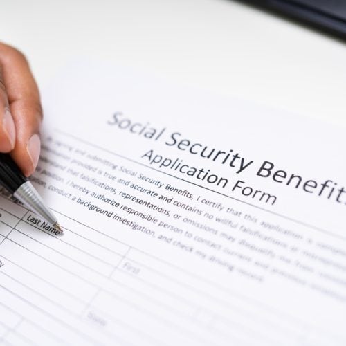 Close up,Of,A,Person's,Hand,Filling,Social,Security,Benefits,Application