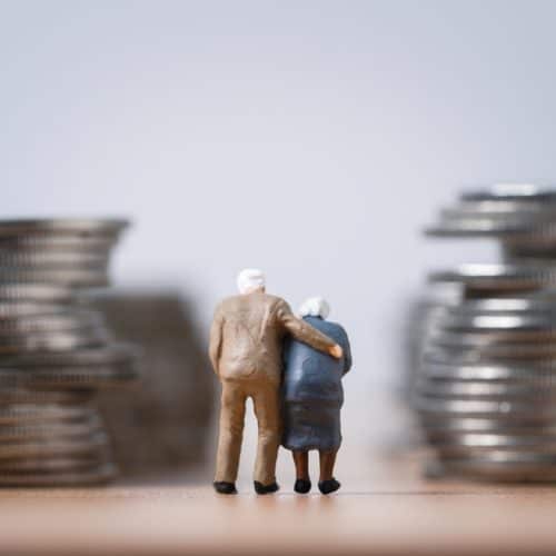 Miniature,Figure,Of,Couple,Senior,Pensioners,Standing,Between,Coins,Stacking