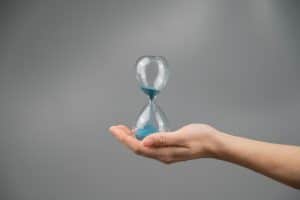 Woman,Holding,An,Hourglass,On,A,Gray,Background.,Close up.,Copy